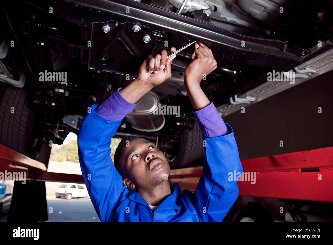 Afrikanischen Mechaniker stehen unter einem Auto, arbeiten am Motor Stockfoto