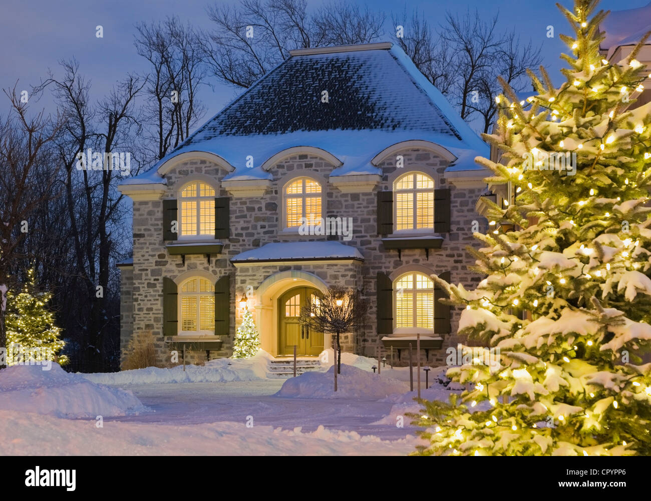 Luxuriöses Wohn-Cottage-Stil mit beleuchteten immergrüne Bäume in der Dämmerung im Winter, Quebec, Kanada Stockfoto