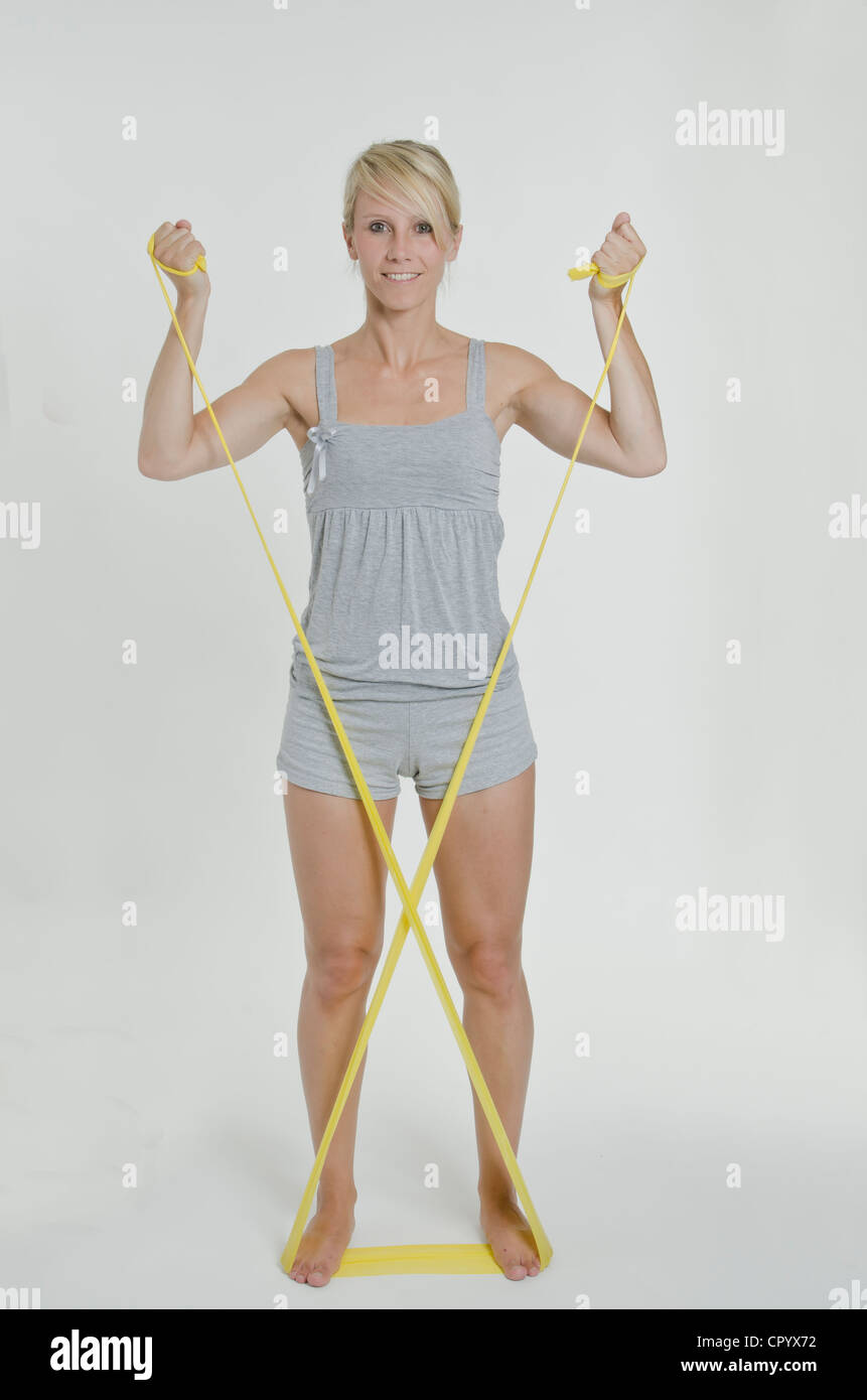 Junge Frau mit einem gelben Gymnastik Band zwischen ihre Hände und Füße bilden ein Kreuz Stockfoto