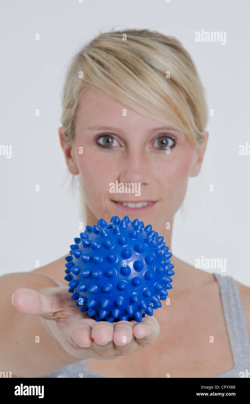 Junge Frau mit ihrem Arm ausgestreckt und hielt eine blaue stacheligen Massageball in ihrer hand Stockfoto
