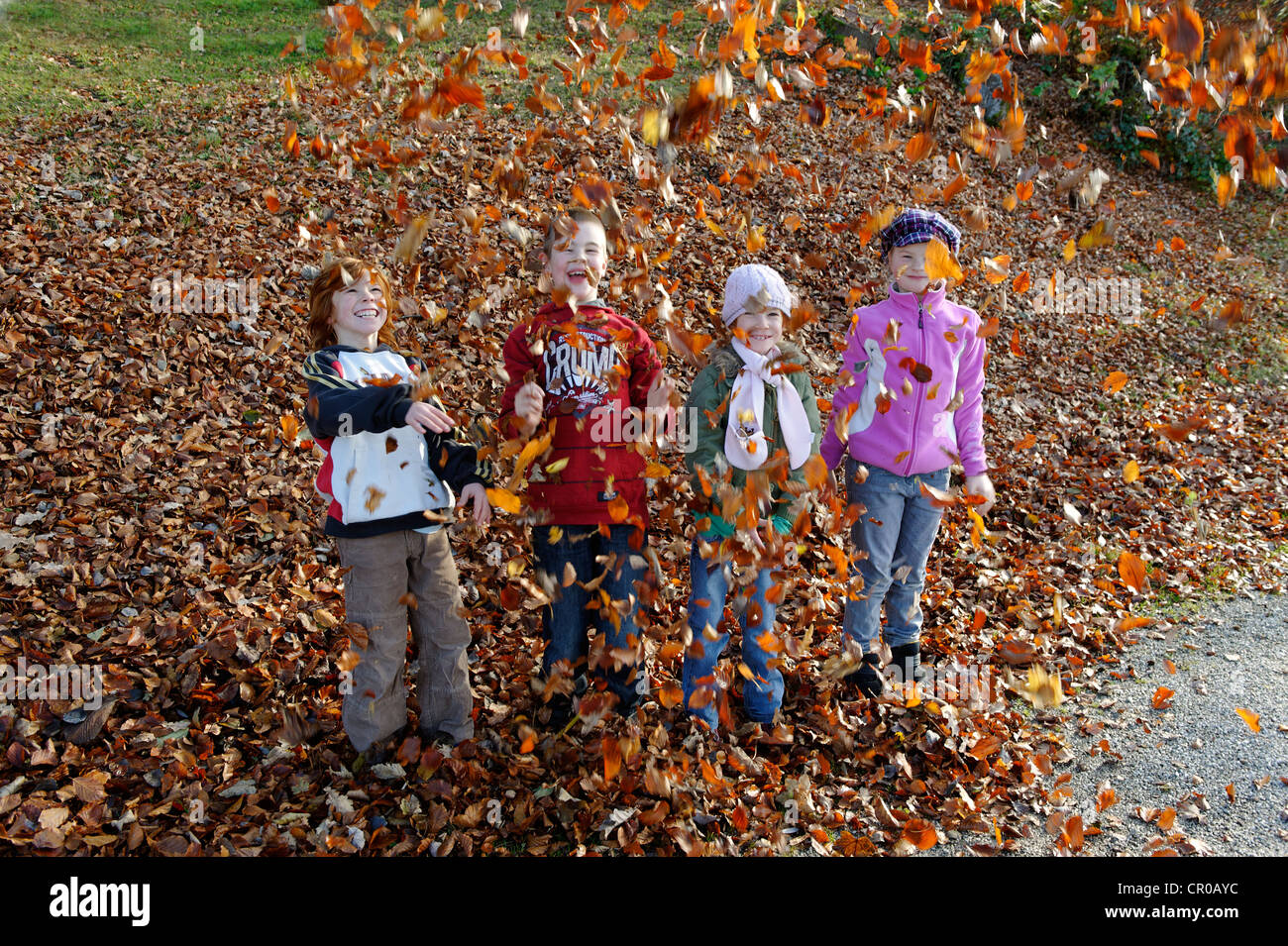 Kinder spielen mit Blättern im Herbst Stockfoto