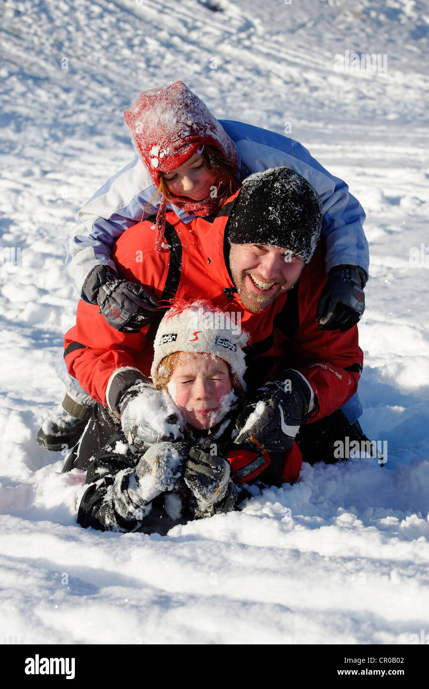 Kinder spielen mit ihrem Vater im Schnee Stockfoto