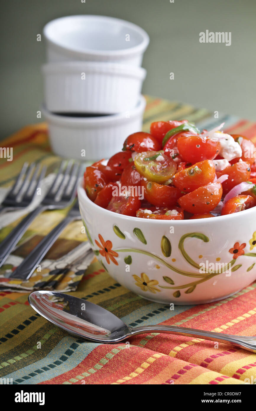 Eine dekorative Schale der Tomate-Feta-Käse-Salat auf 3 anderen in weißen Förmchen mit 3 Gabeln und ein Löffel dienen. Stockfoto