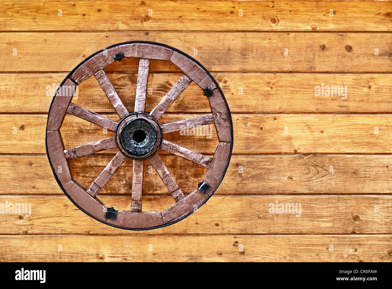 Ein altes Wagenrad, dekoriert mit einer Holzwand Stockfoto