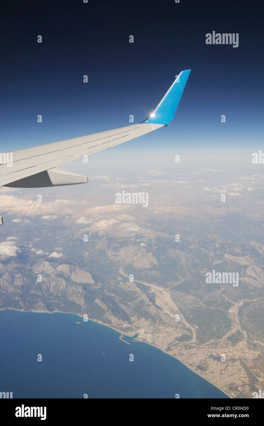 Flugzeugflügel unter Berge und Meer Stockfoto