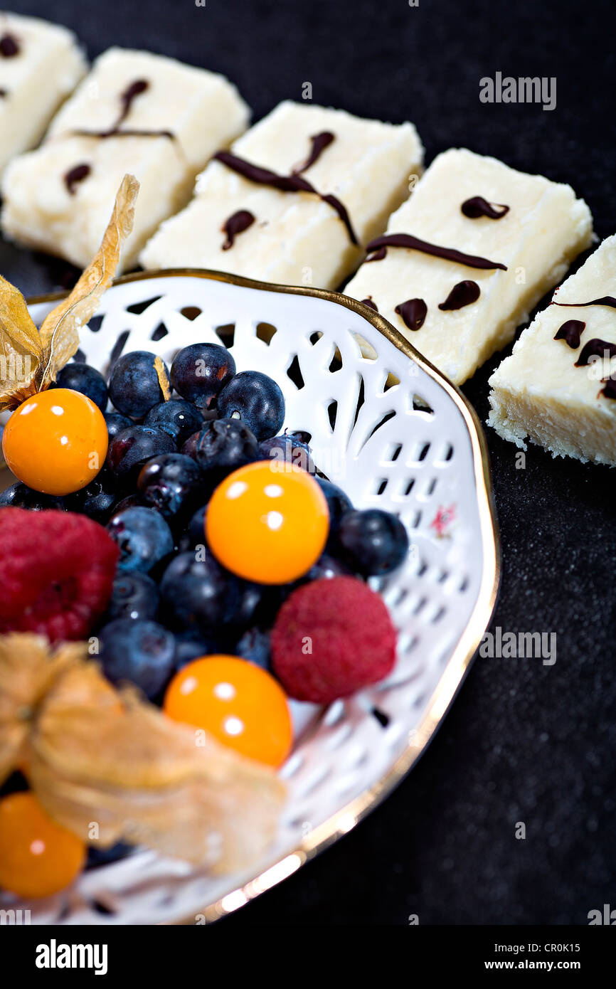 Domino-Cocos-Süßwaren mit Schokolade und eine Schüssel mit gemischten Beeren Stockfoto