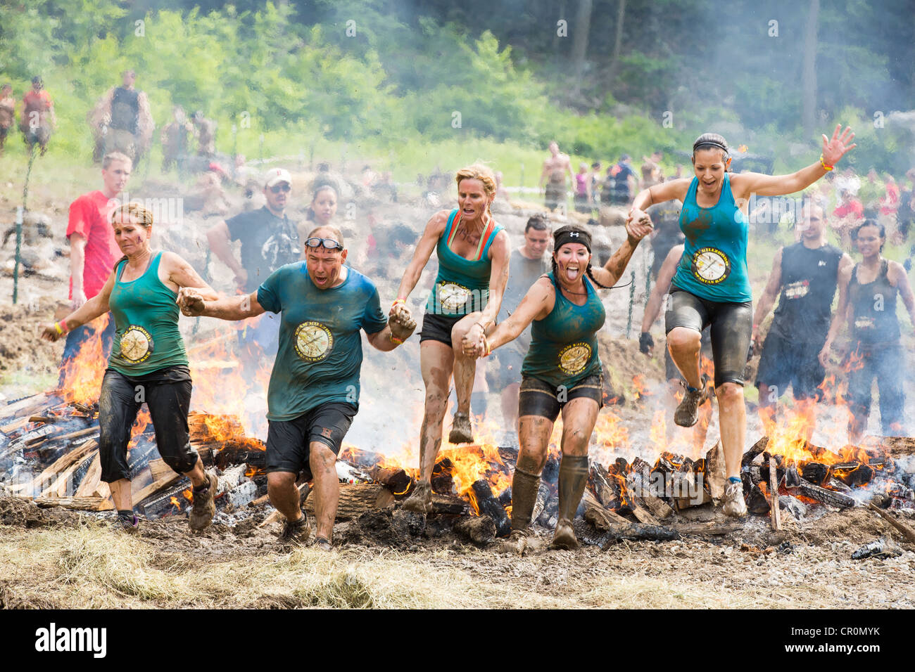 Teilnehmer des schwierigen Hindernis Trail Sprintrennen, Spartan Race Sprung Feuer während Hand in Hand. Stockfoto Teilnehmer des schwierigen Hindernis Trail Sprintrennen, Spartan Race Sprung Feuer während Hand in Hand. Stockfoto