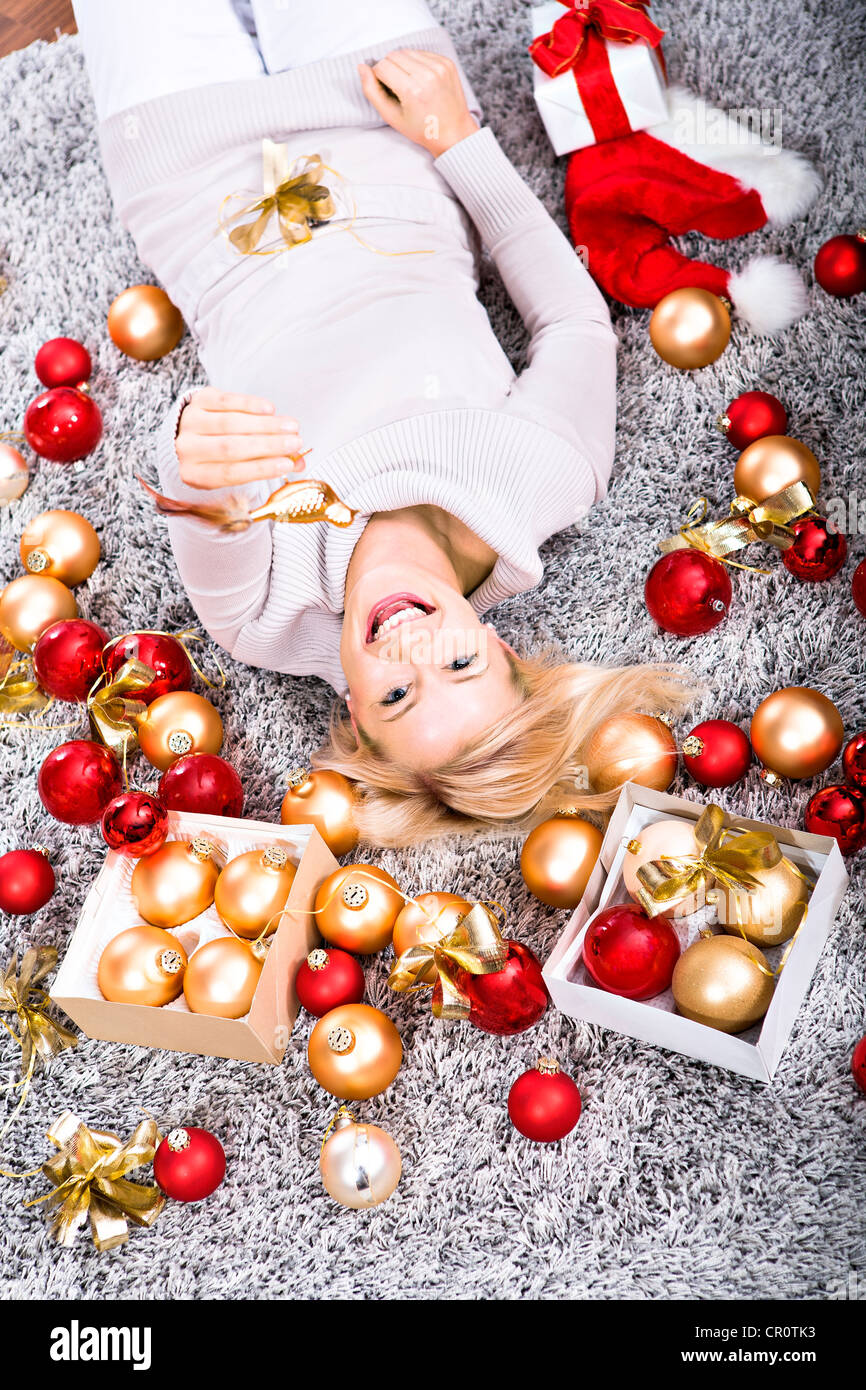 Junge Frau liegt inmitten von Weihnachtsschmuck Stockfoto