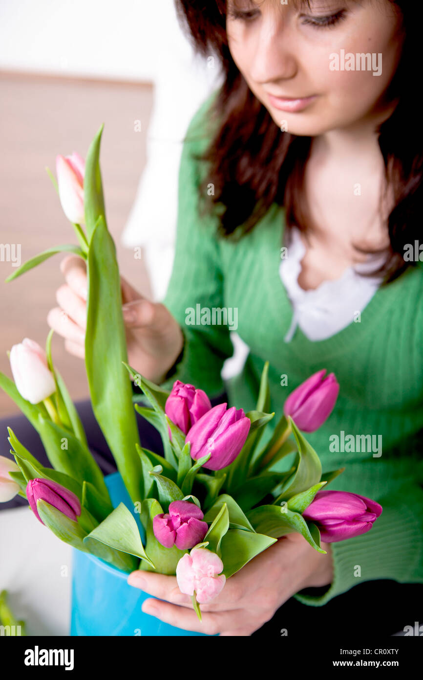 Junge Frau, die Vermittlung von Tulpen in einer vase Stockfoto