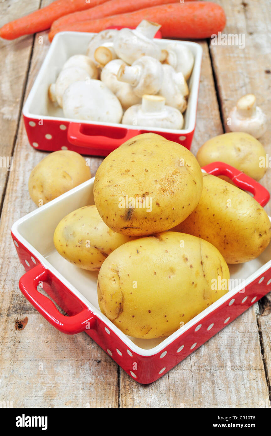 Rohe Pilze und Kartoffeln in roten Schalen Stockfoto