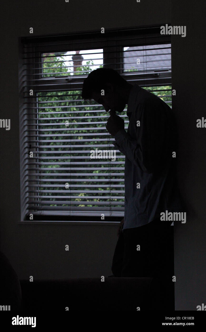 Profil von einem jungen männlichen durch ein Fenster mit Jalousie. Silhouette. Stockfoto