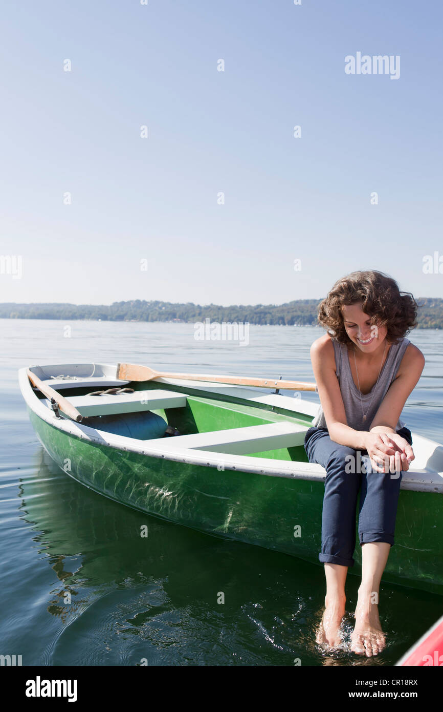 Frau baumelnden Füße vom Boot im See Stockfoto