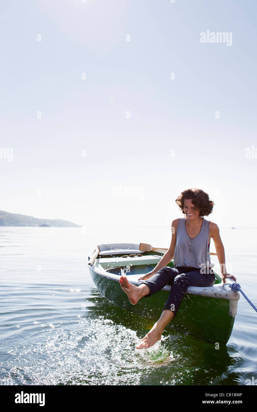 Frau baumelnden Füße vom Boot im See Stockfoto