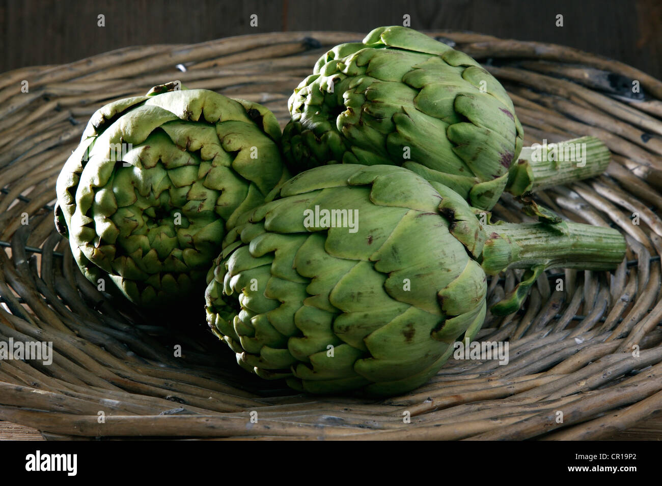 Drei Artischocken (Cynara Cardunculus) in einem Korb Stockfoto