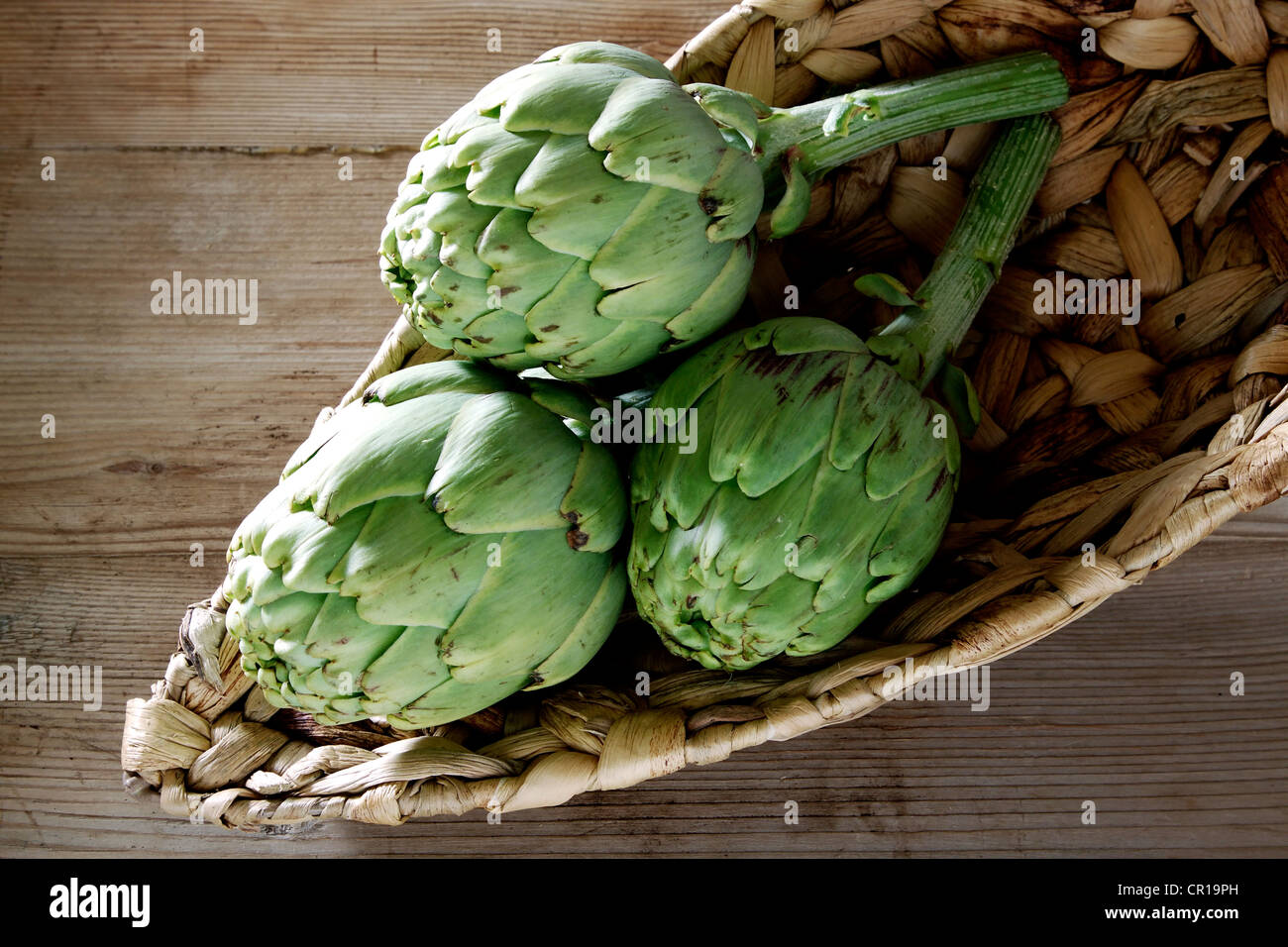 Drei Artischocken (Cynara Cardunculus) in einem Korb Stockfoto