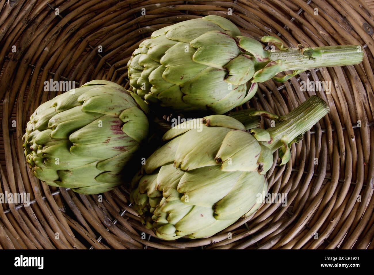 Drei Artischocken (Cynara Cardunculus) in einem Korb Stockfoto