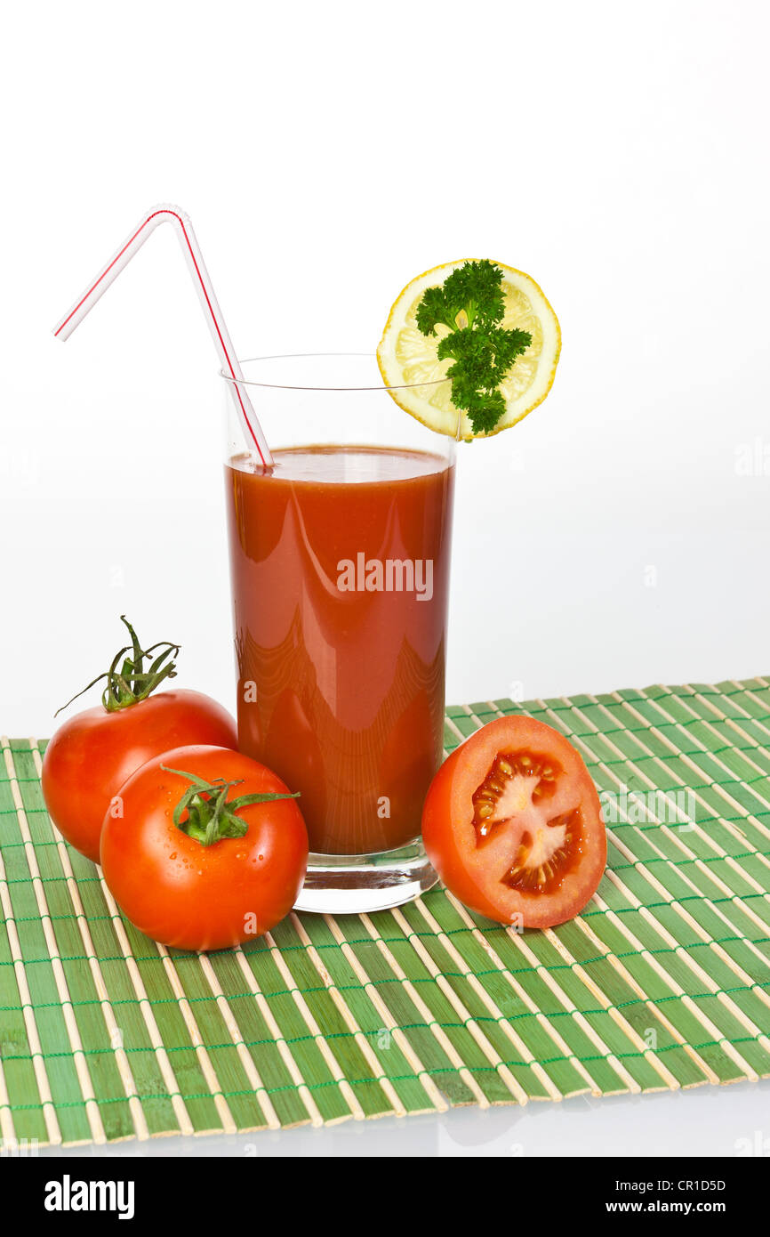 Tomatensaft in einem Glas mit Tomaten und Zitrone Stockfoto