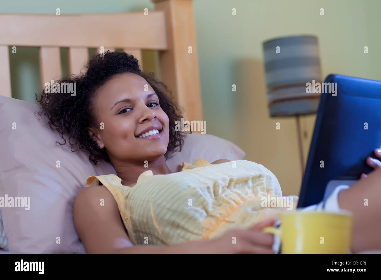 Lächelnde Frau auf Bett lesen Stockfoto