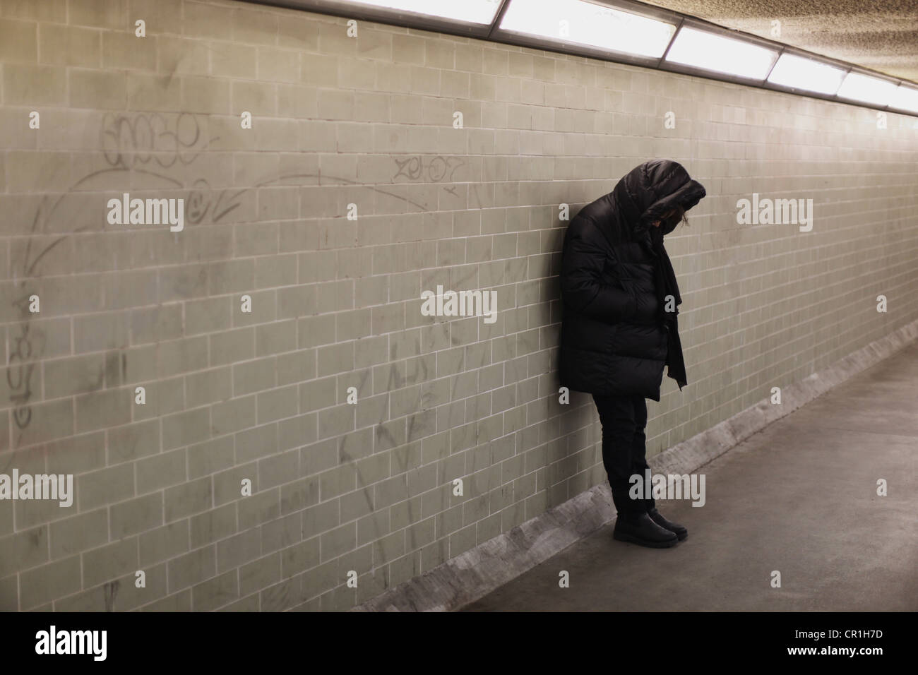 Vermummte Person stützte sich auf u-Bahn-Wand Stockfoto