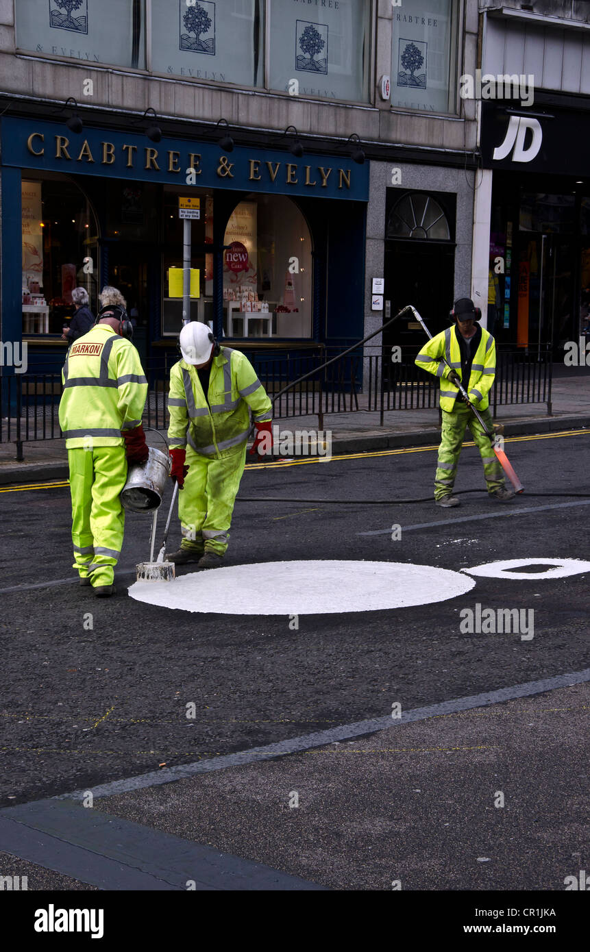 Männer gehen über in die immer größer werdende Kreise malen einen Kreisverkehr im Zentrum von Edinburgh, Schottland. Stockfoto