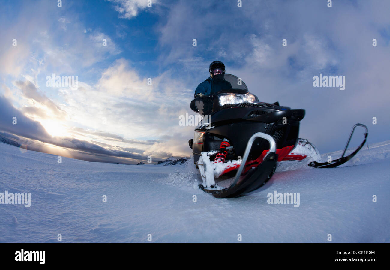 Mann fahren mit Motorschlitten in schneebedecktes Feld Stockfoto