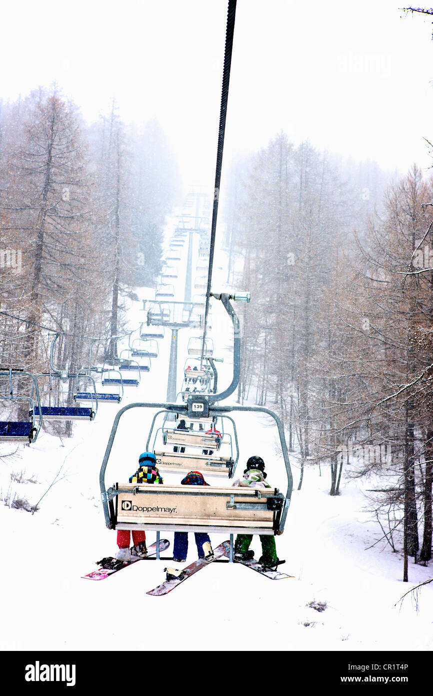 Snowboarder am Skilift Stuhl während Blizzard Schneesturm in Bardonecchia Italien Stockfoto