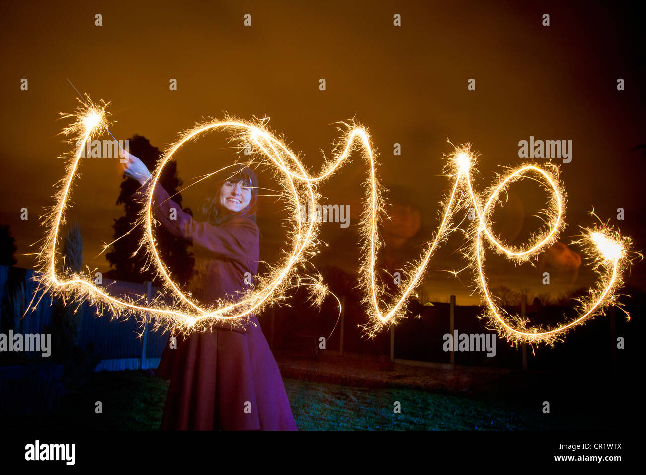 Frau schreiben Liebe mit Wunderkerze Stockfoto