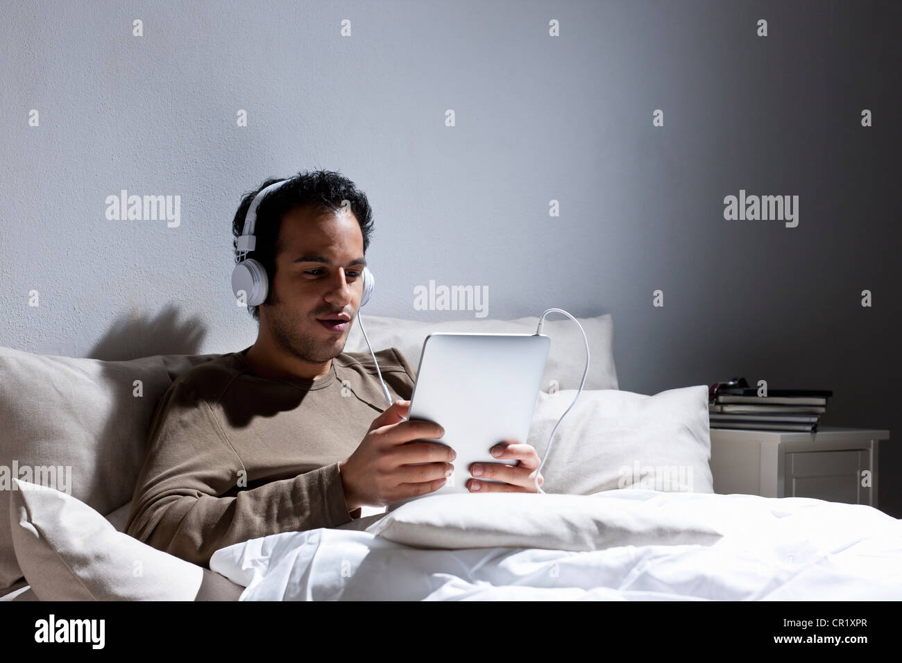 Mann mit Tablet-PC im Bett Stockfoto