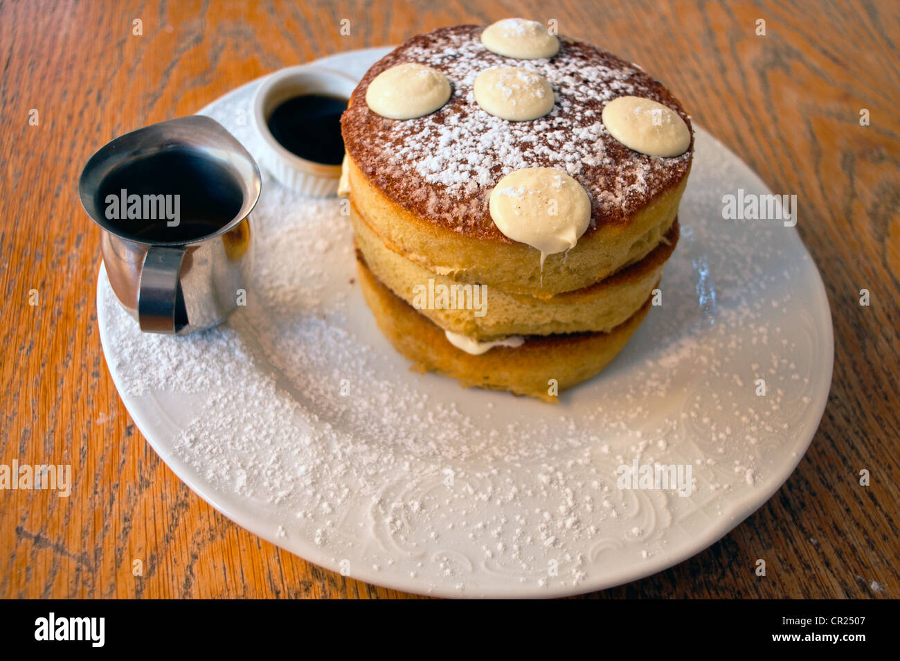 Drei dicke Pfannkuchen mit weißen Schokoladen-Münzen, Ahornsirup und kleinen Espresso-Dekanter Stockfoto