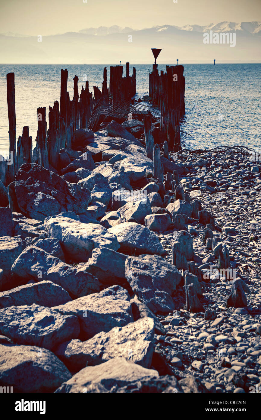 Wellenbrecher mit Haufen von Holz und Steinen in einem Bergsee Stockfoto