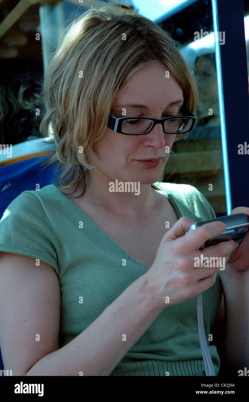 Junge Frau in einem Zug Blick auf ein Foto mit ihrer Kompaktkamera. Stockfoto