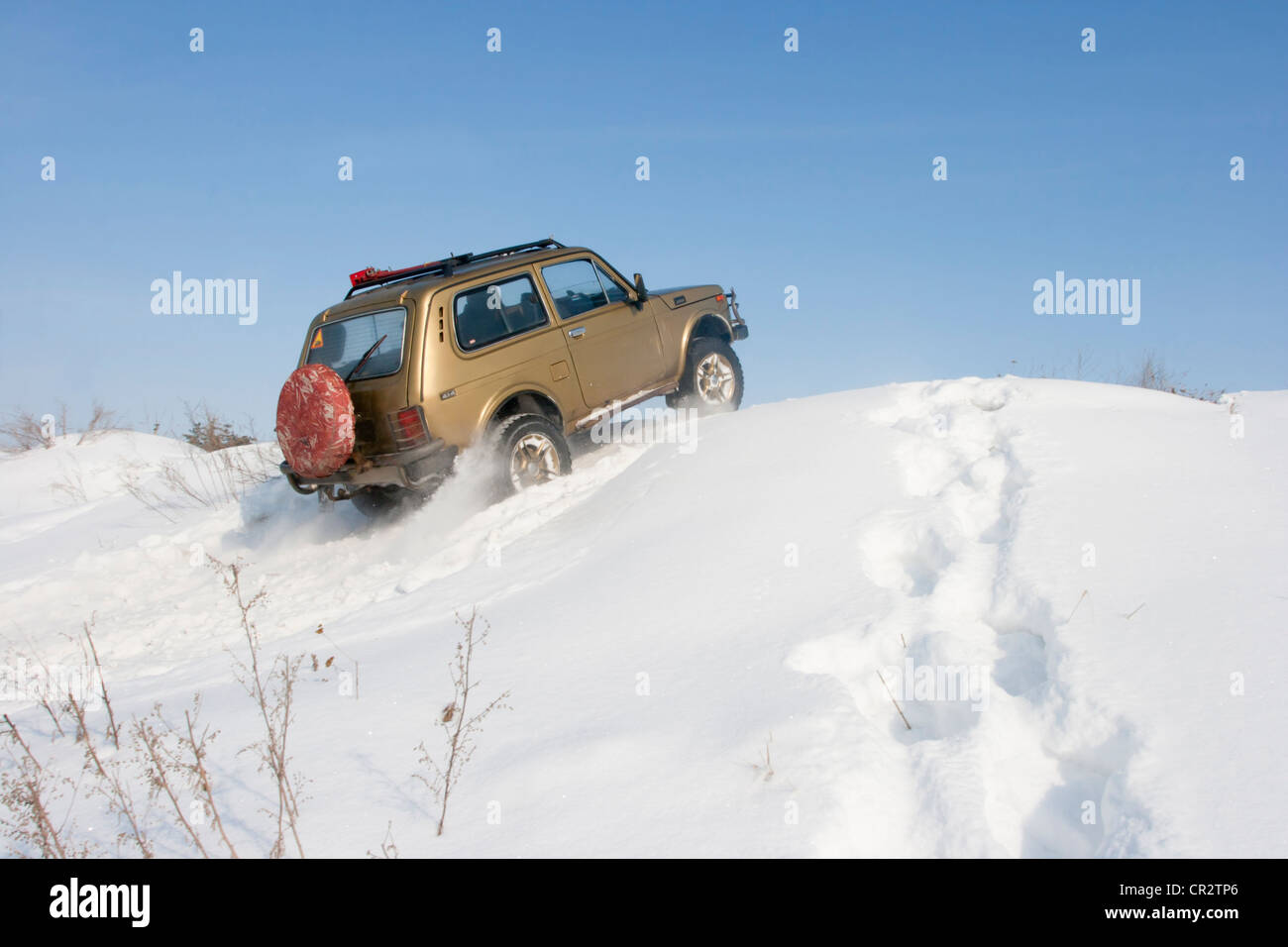 Lada Niva SUV Jeep fährt auf dem schneebedeckten Hügel. Das Schild an der Heckscheibe ist nicht urheberrechtlich geschützt. Stockfoto