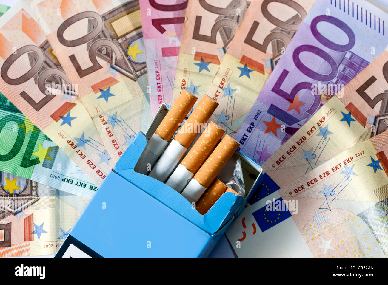 Rauchen kostet Geld, Euro-Banknoten und Zigaretten Stockfoto