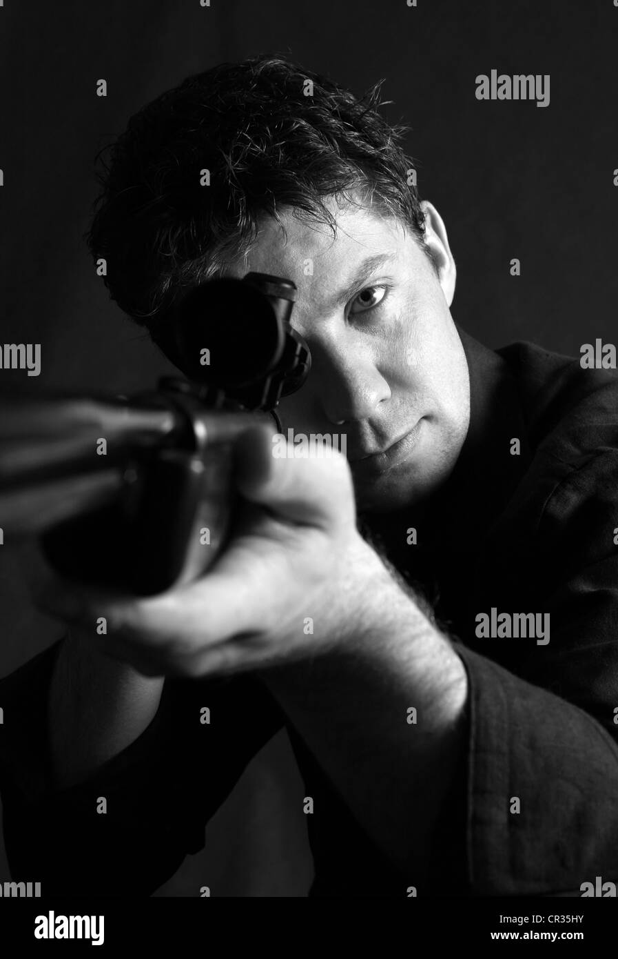 Der Mann mit der Waffe im Studio auf einem schwarzen Hintergrund Stockfoto