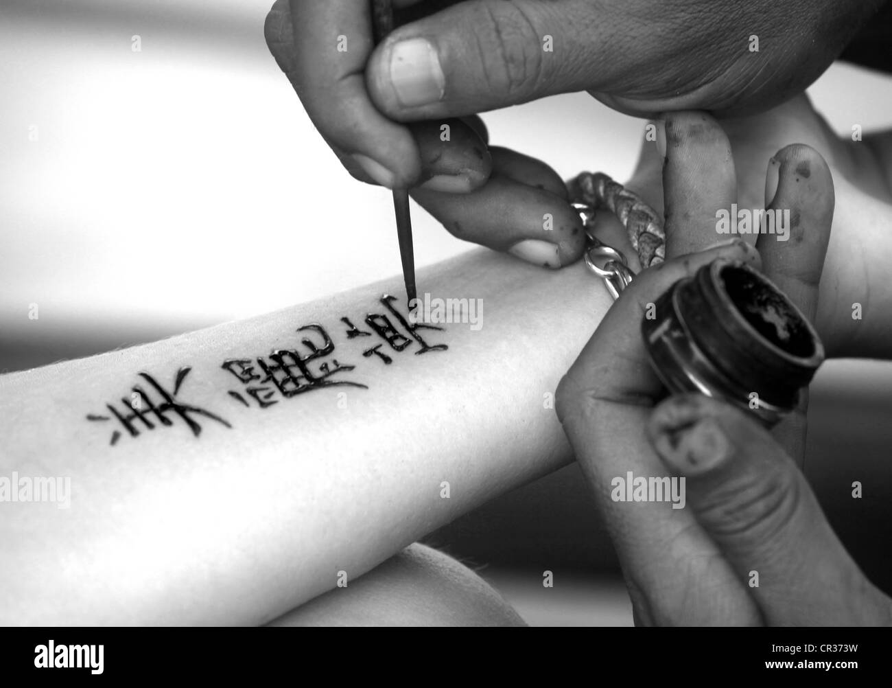 Künstler zeichnet ein Henna Tattoo auf eine weibliche Hand. Hieroglyphe "Schöner Traum" Stockfoto