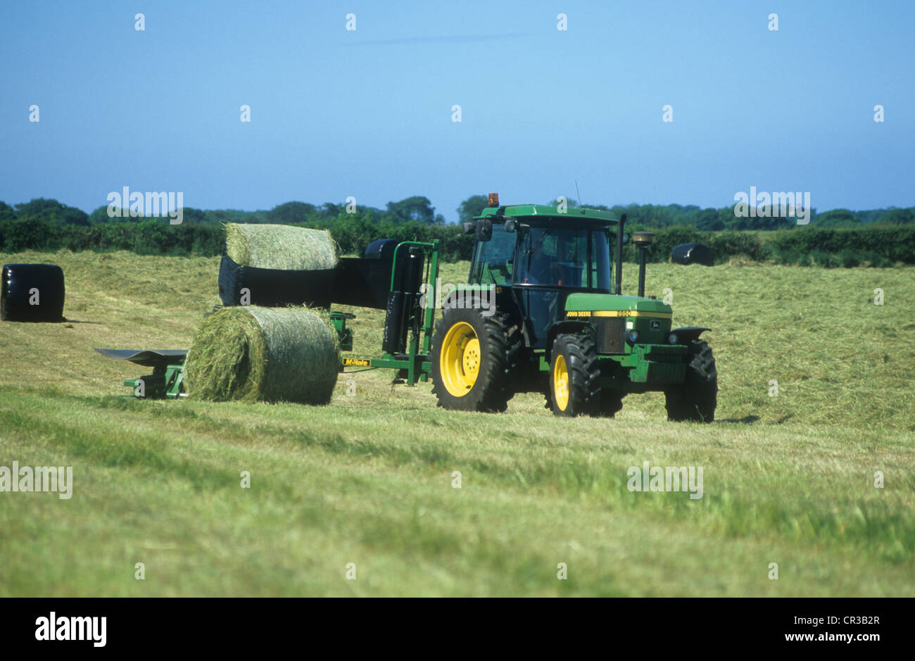 John Deere Traktor-2850 Abschleppen und umschließt Heuballen in Polyuthane Folie für Lagerung und Tier Feeds in den Wintermonaten. Stockfoto