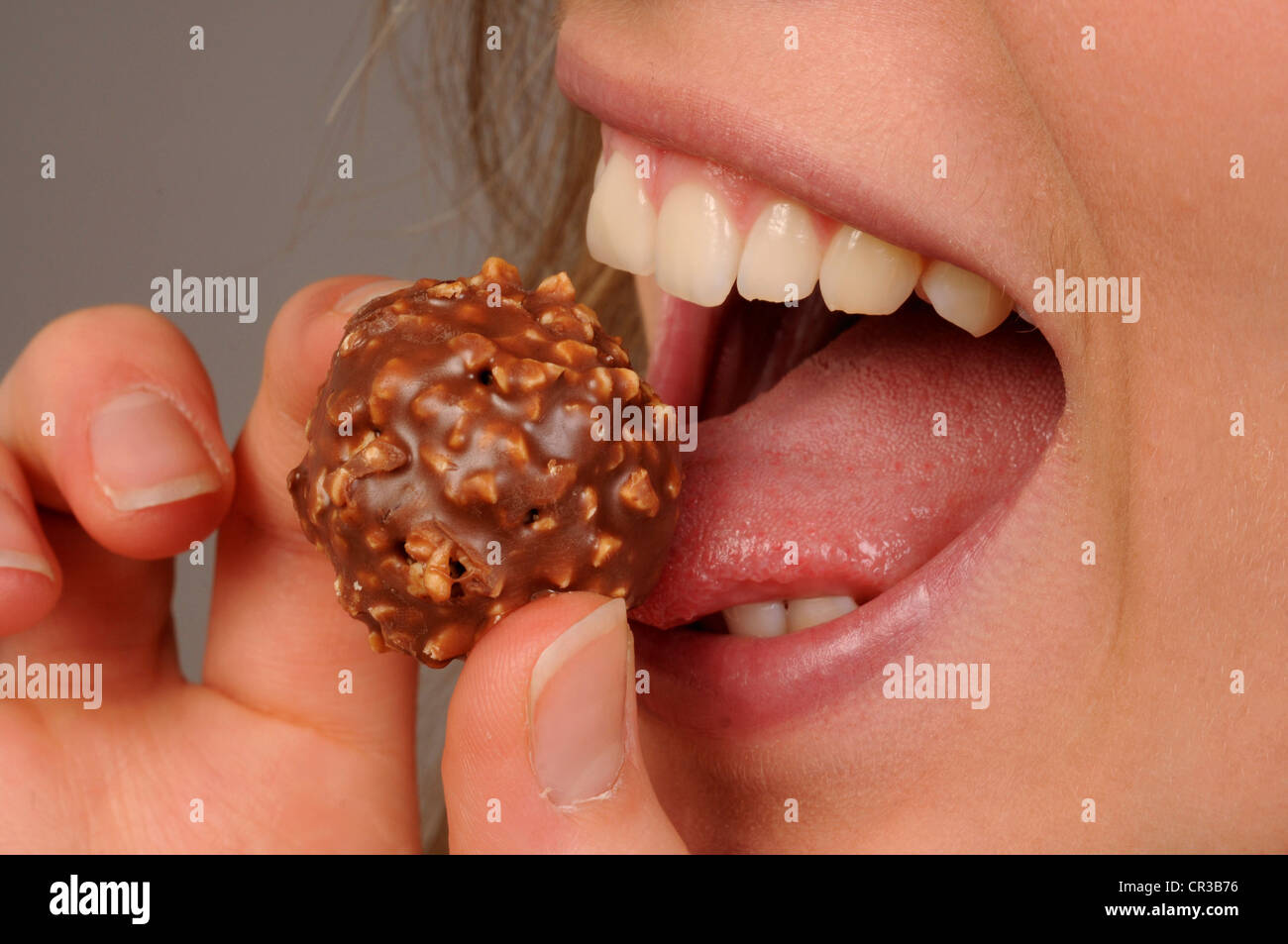 Junge Frau essen Schokolade Kugel, close-up von Mund, Zunge leckt an der Schokolade Stockfoto