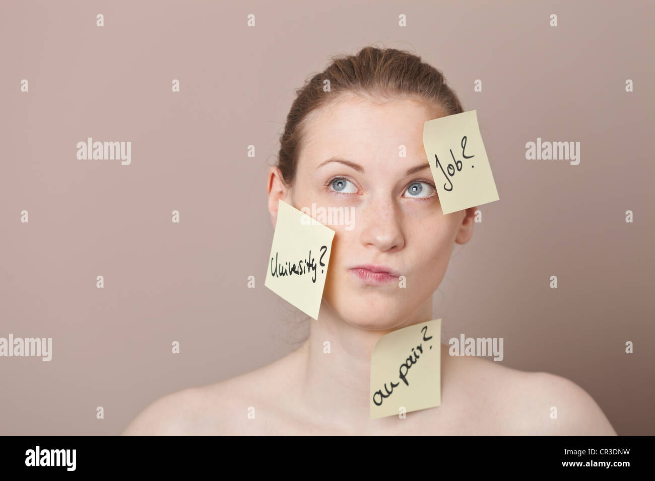 Post-It Zettel geschrieben in deutscher Sprache mit Optionen für die Zukunft, das Festhalten an das Gesicht eines unentschlossenen junge Frau Stockfoto