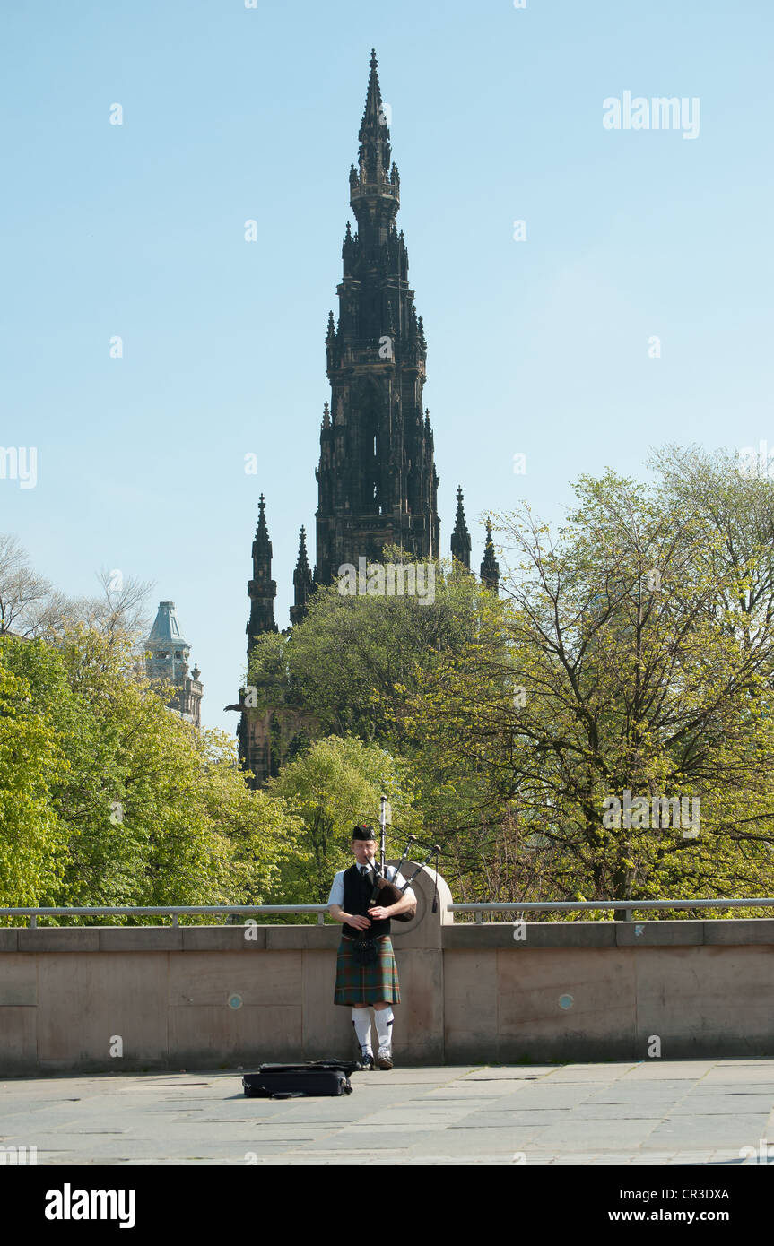 Piper spielt in Edinburgh mit Scott Monument im Hintergrund, Schottland Stockfoto