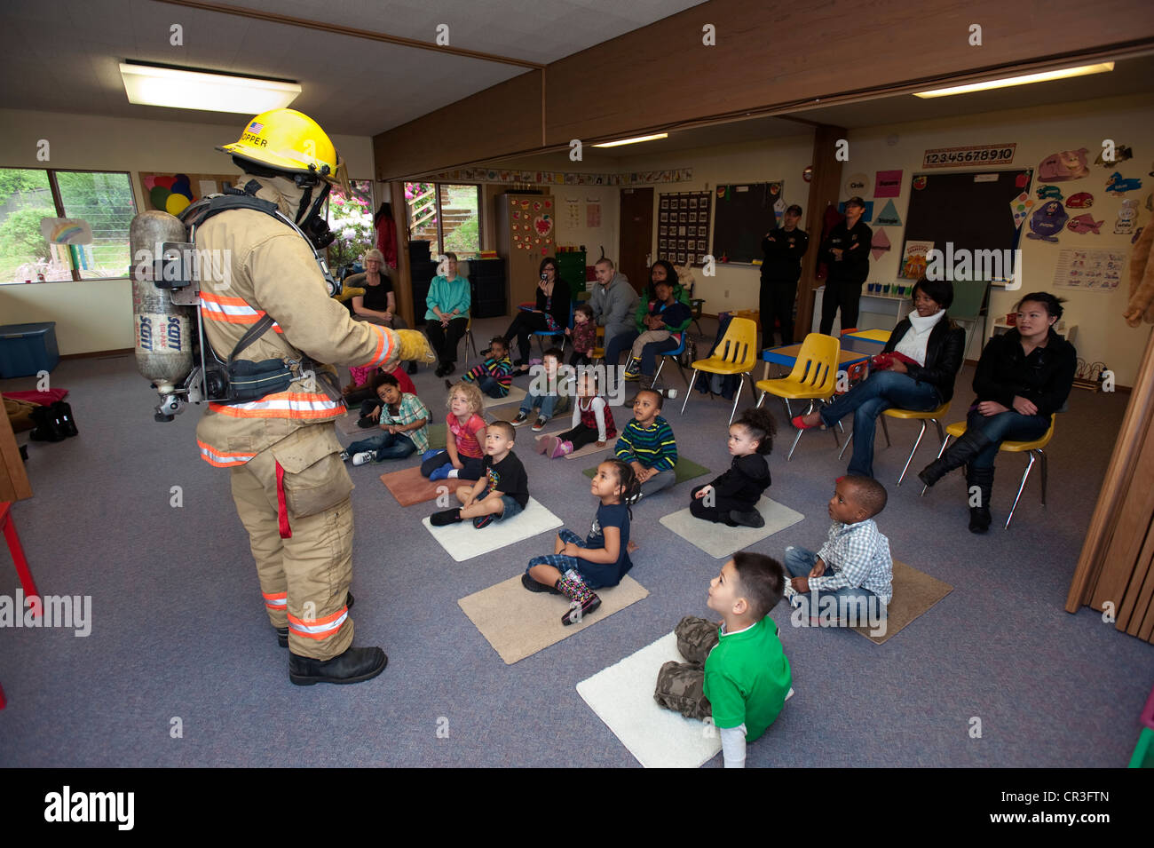 Feuerwehrmann im Gespräch mit Kindern im Vorschulalter. Stockfoto