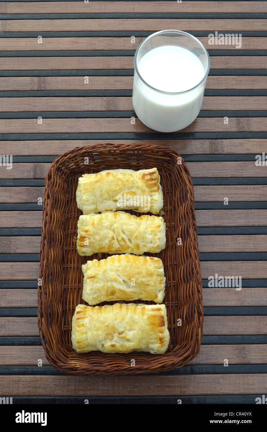 Hausgemachtes Gebäck, gefüllt Blätterteig in einen Frühstückskorb neben ein Glas Milch Stockfoto