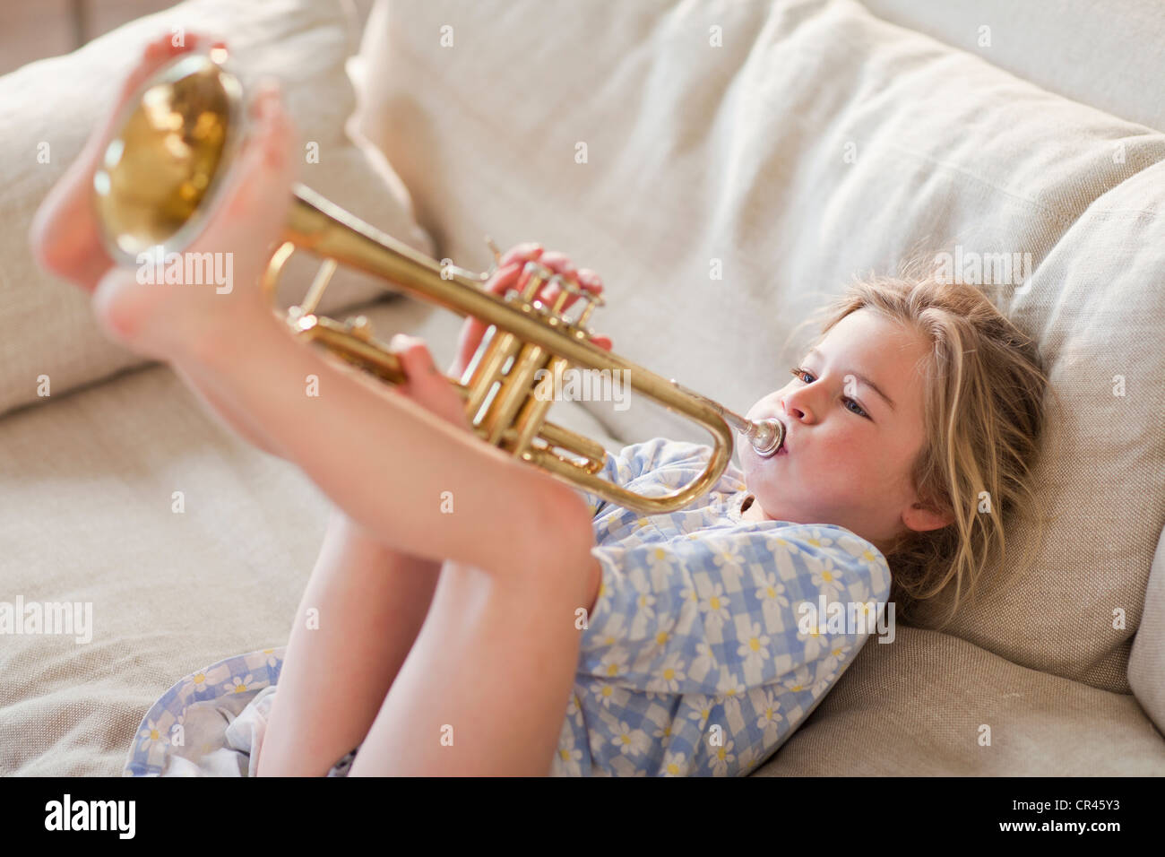 Kaukasische Mädchen auf Sofa, Trompete Stockfoto