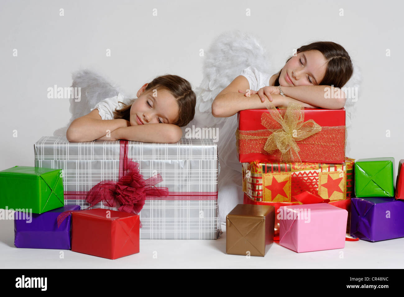 Zwei müde Mädchen verkleidet als Weihnachtsengel mit Geschenken, Weihnachten Stockfoto