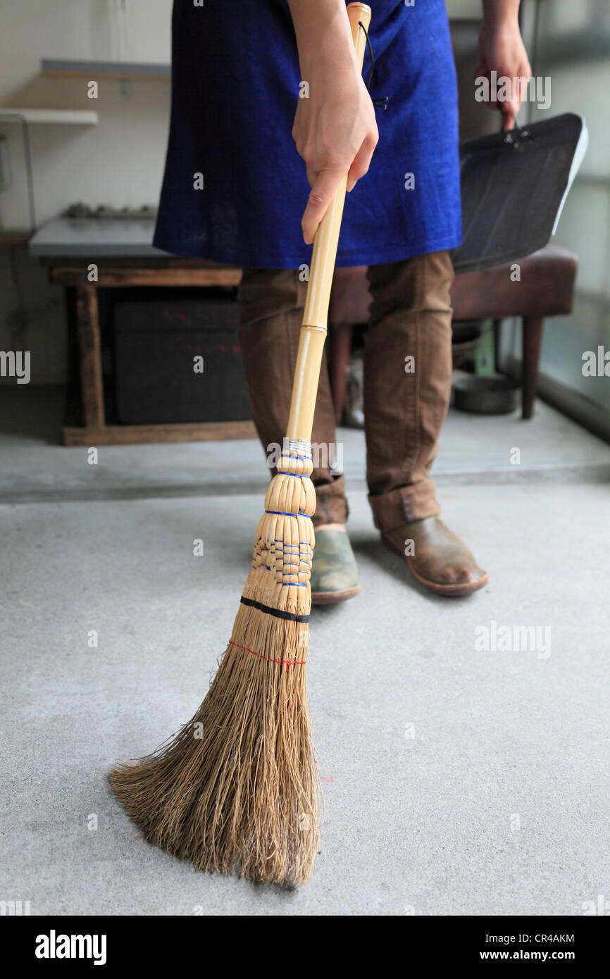 Junge Frau fegen Zimmer mit Besen Stockfoto