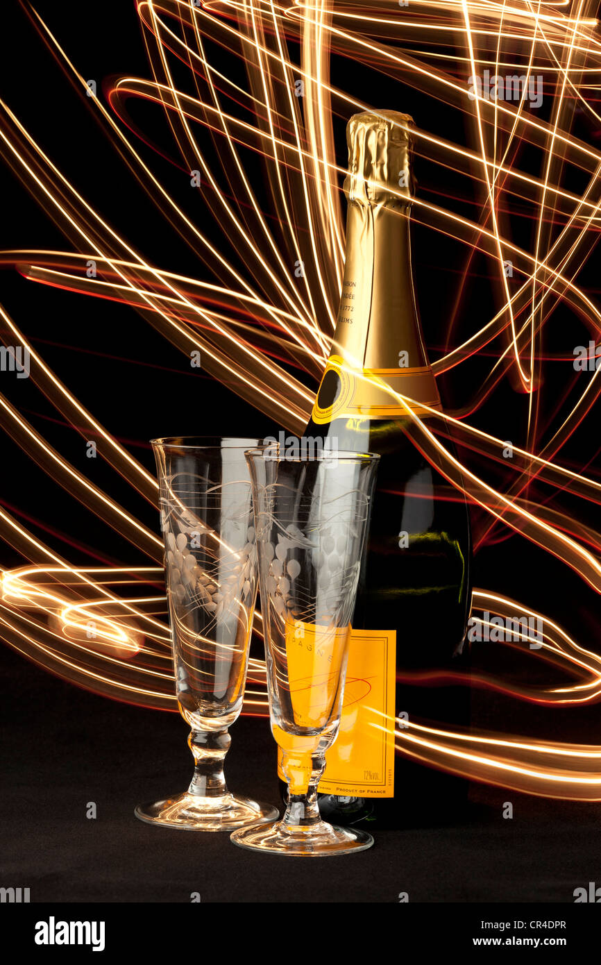 Rot und gold Lichtspuren wirbeln um eine Flasche Champagner und zwei Gläser Champagnerglas Stockfoto