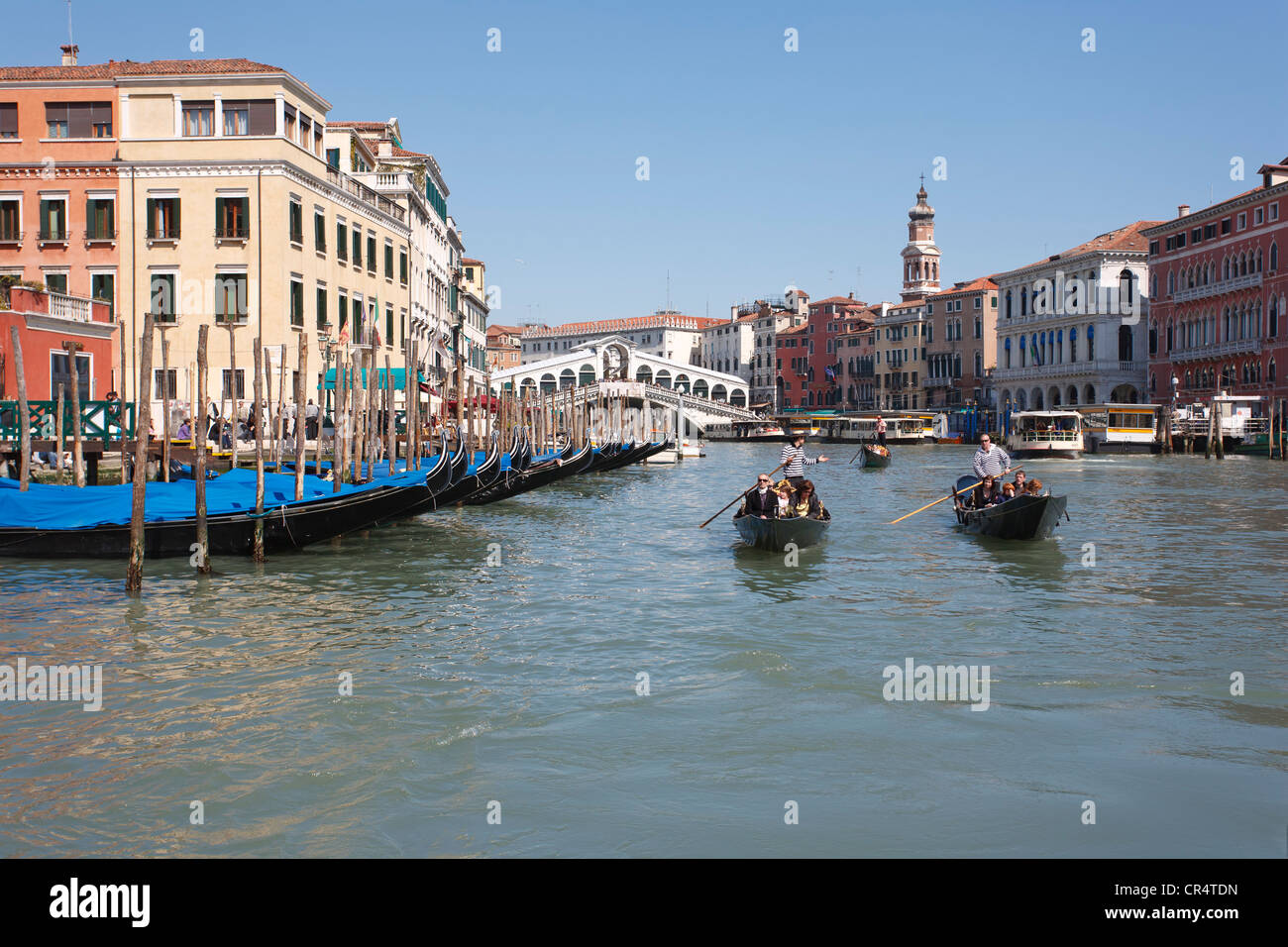 Canal Grande, angedockt Canal Grande mit der Rialtobrücke, Gondolieri in venezianischen Gondeln vorbei Gondeln, Venedig, Italien Stockfoto