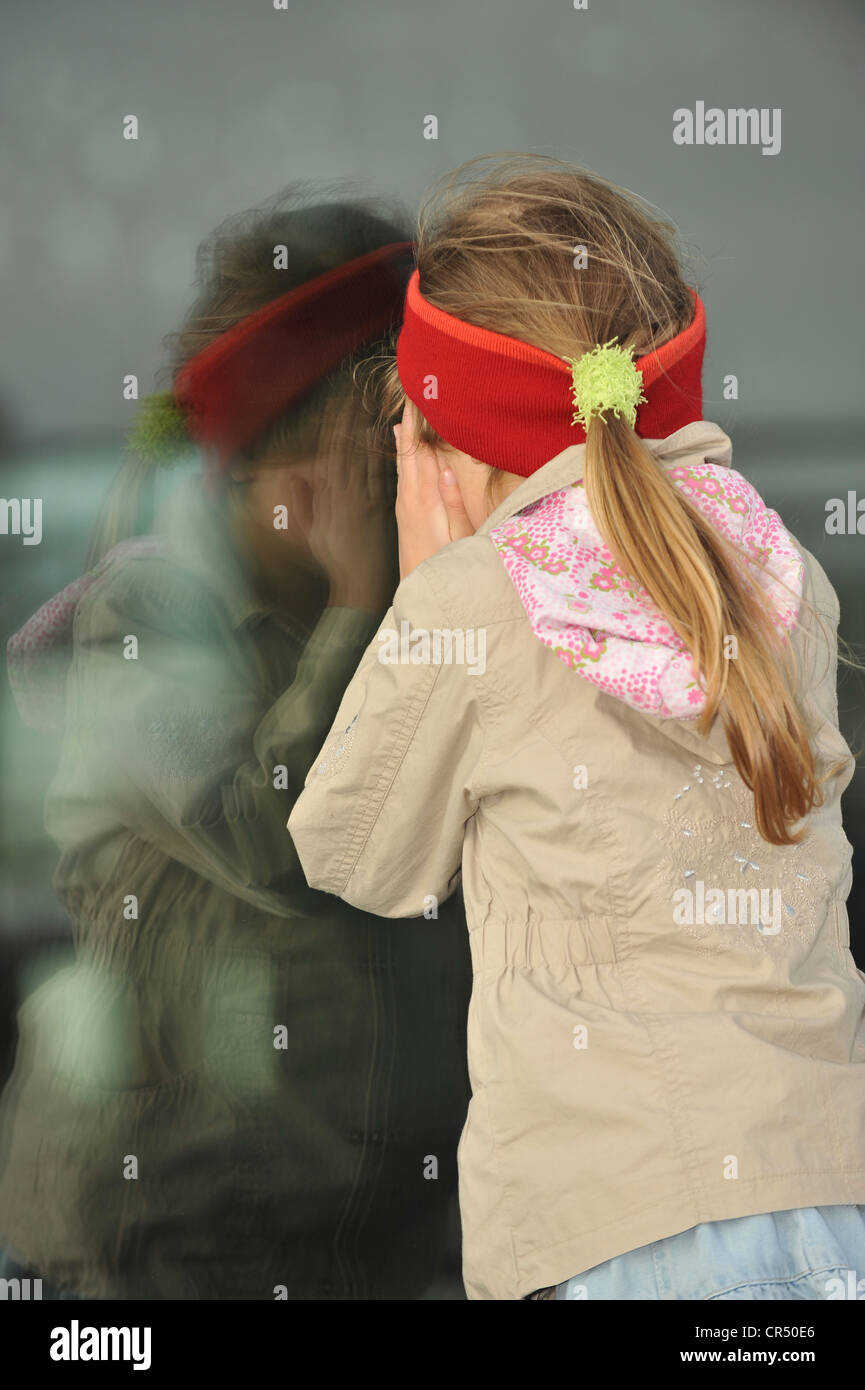 Mädchen, 6 Jahre, Blick durch ein verspiegeltes Glas-Oberfläche Stockfoto