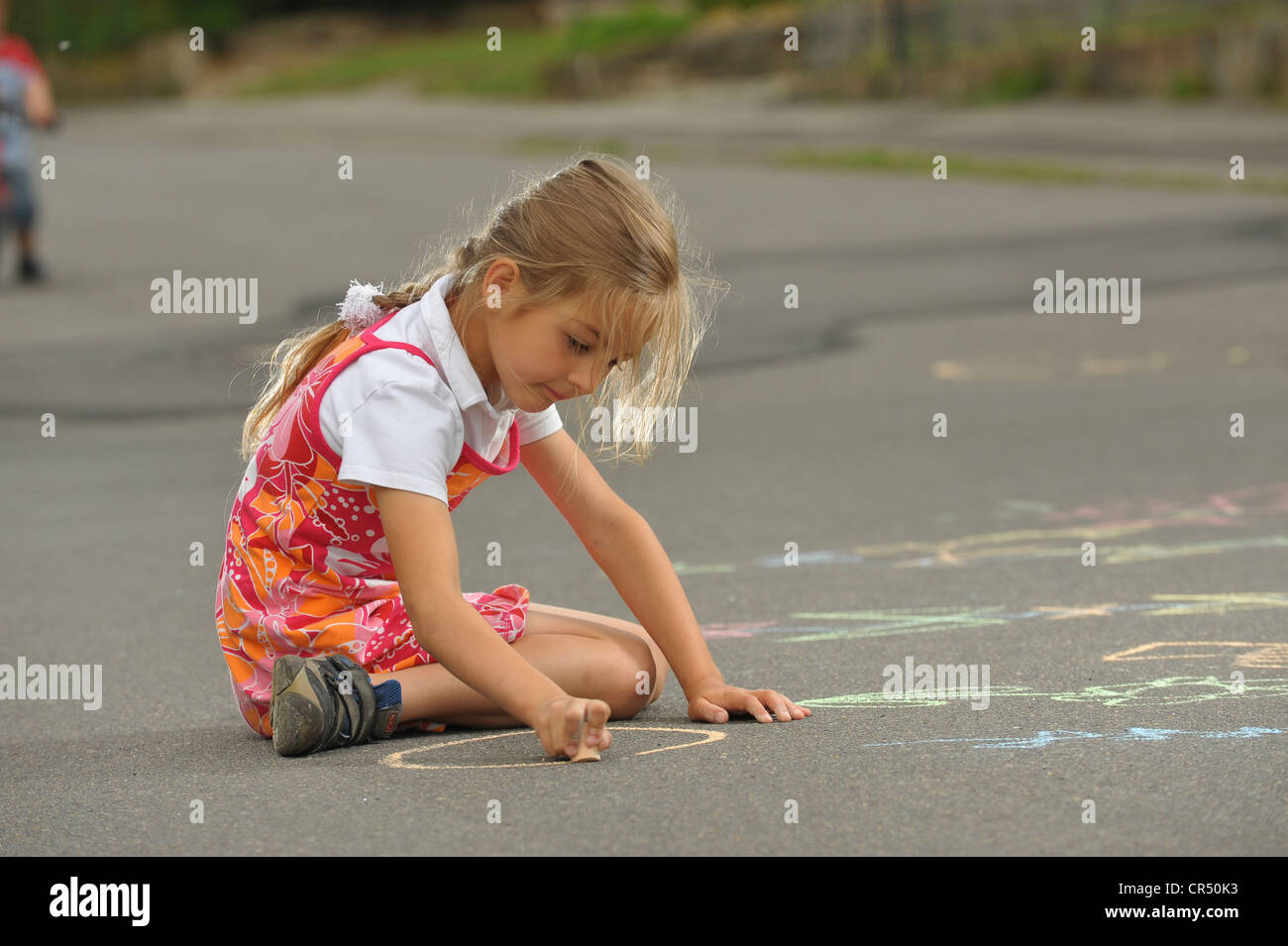 Mädchen, ca. 6 Jahre, Malen mit Kreide auf asphalt Stockfoto