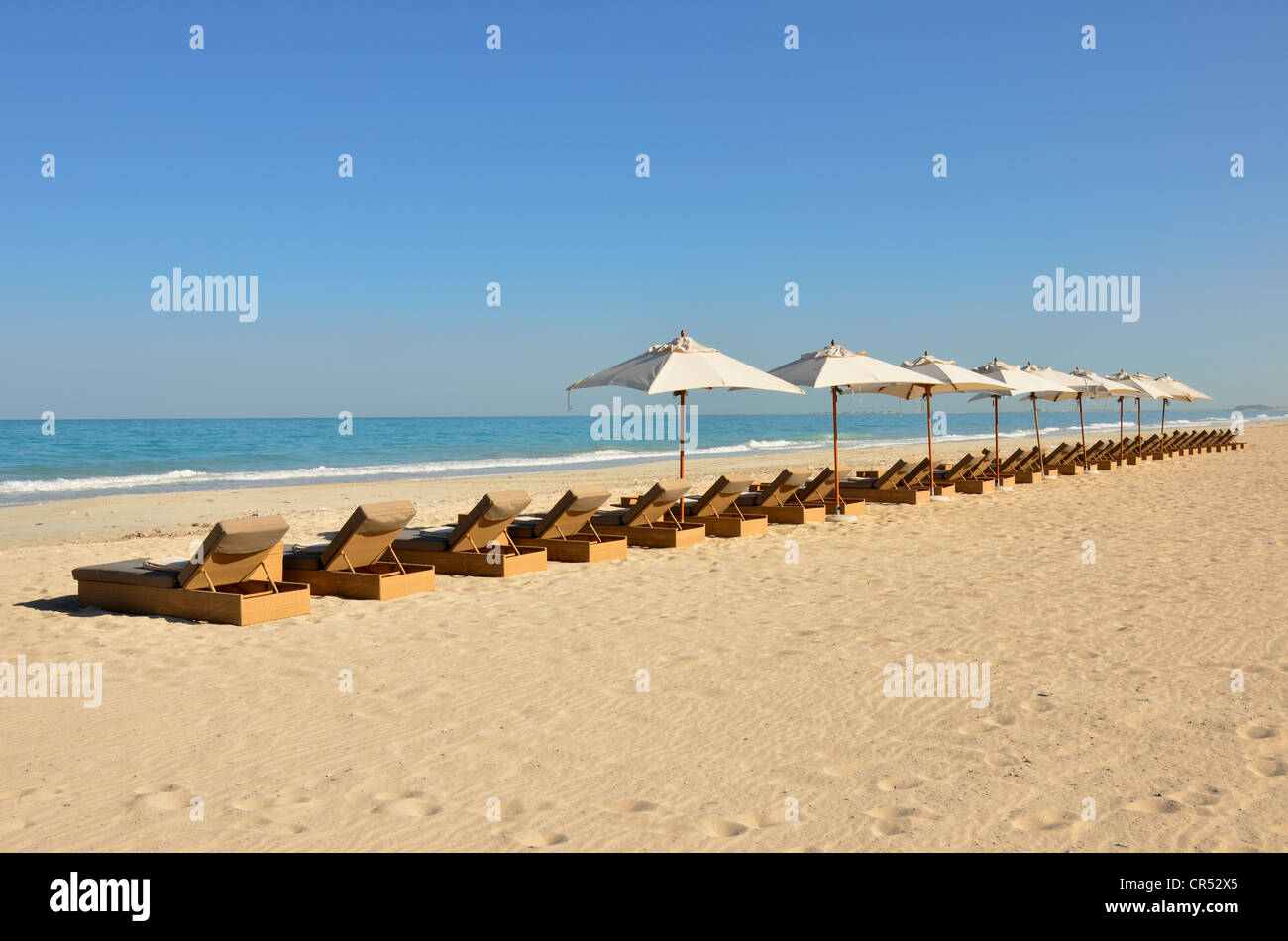 Sonnenliegen und Sonnenschirme am Strand des Park Hyatt Hotel auf Saadiyat Island, Abu Dhabi, Vereinigte Arabische Emirate Stockfoto