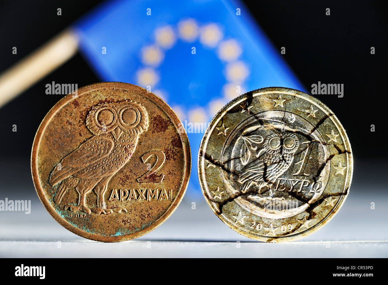 Griechische Drachme und eine griechische ein-Euro-Münze mit Rissen vor der EU-Flagge Stockfoto